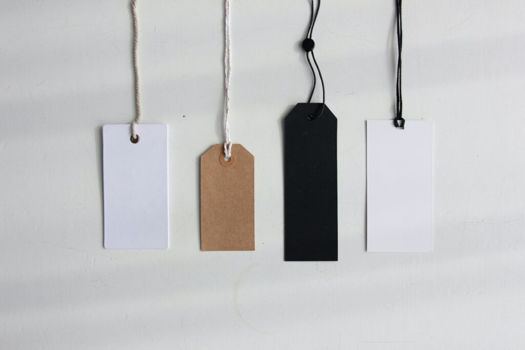 Four blank paper gift tags — white, brown, black, and white — hanging from the top of the frame.