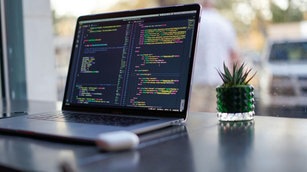 A laptop sitting on a table with code displayed on the screen.
