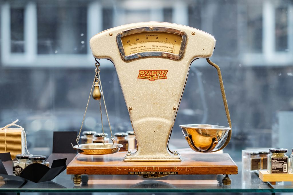 A brown and beige weighing scale with two empty golden dishes.