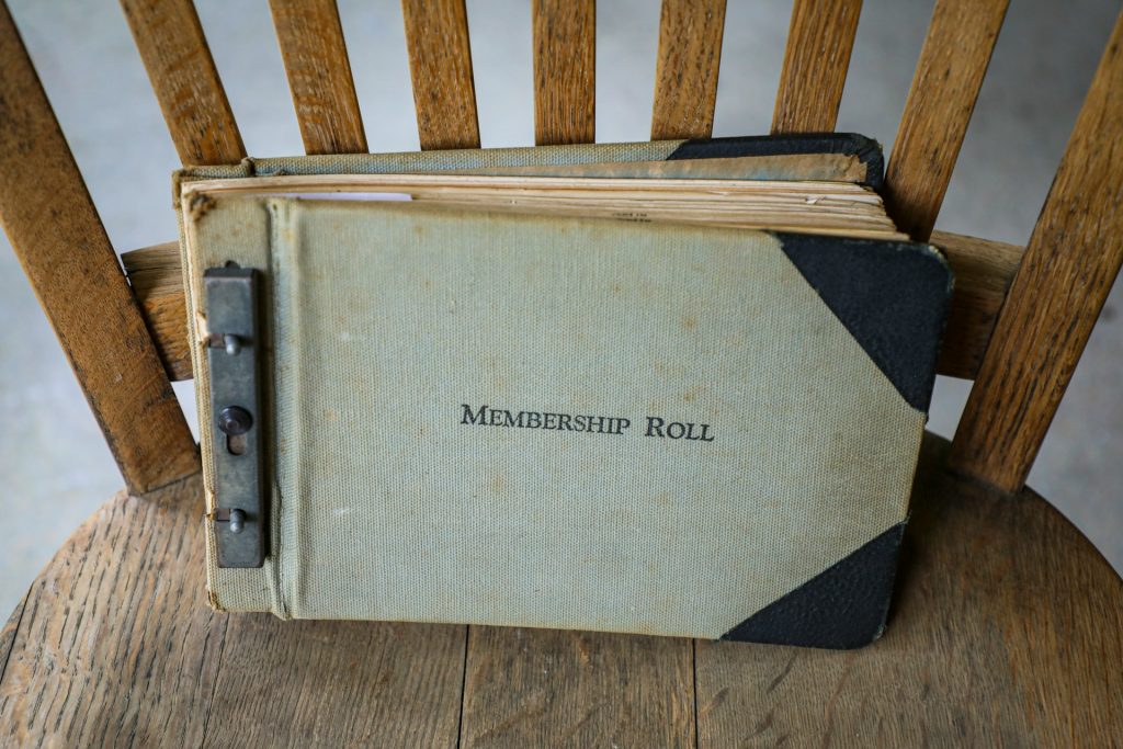 An old notebook labeled "Membership Roll" sitting on a wooden chair