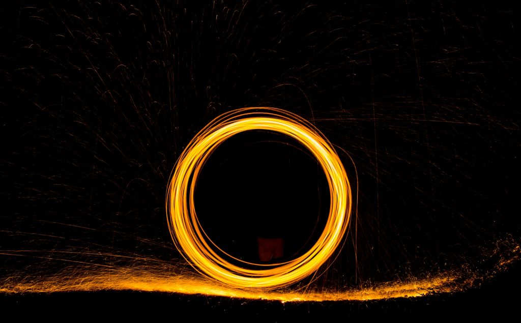 Long exposure photo of sparks in front of a dark background making a circle
