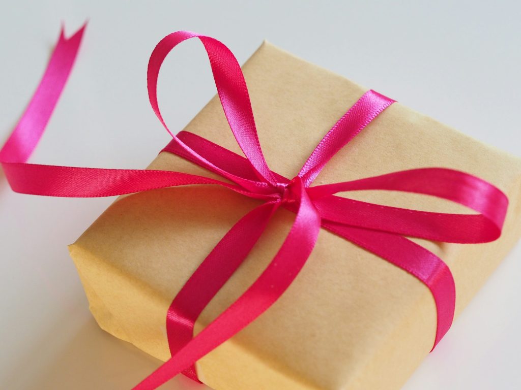 A square package wrapped in brown paper with a pink ribbon