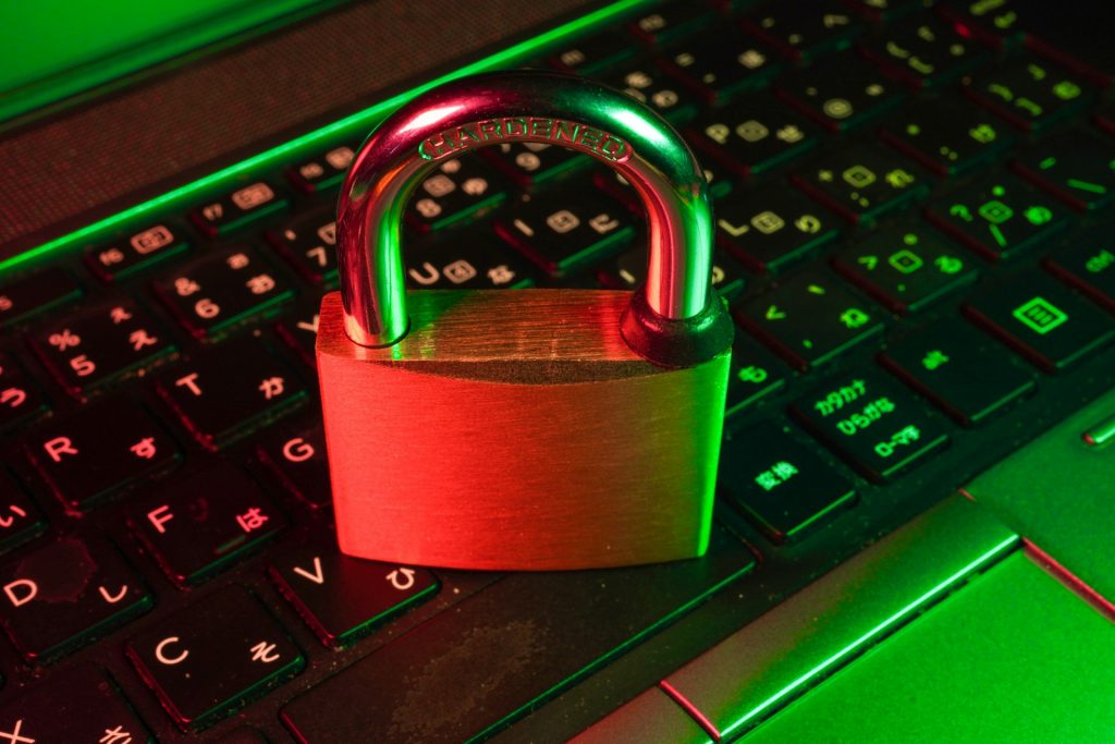 A small metal padlock sitting atop a computer keyboard with black keys bathed in red and green light.