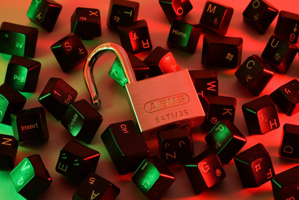 An open padlock lying on a pile of keyboard keys in green and red lighting.