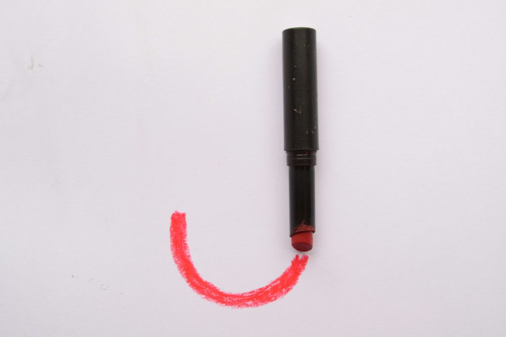 A red mark drawn on a white background by a marker in black case. Together they form a J shape.