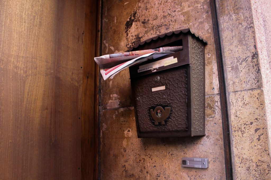 An over-filled mail box attached to a wall